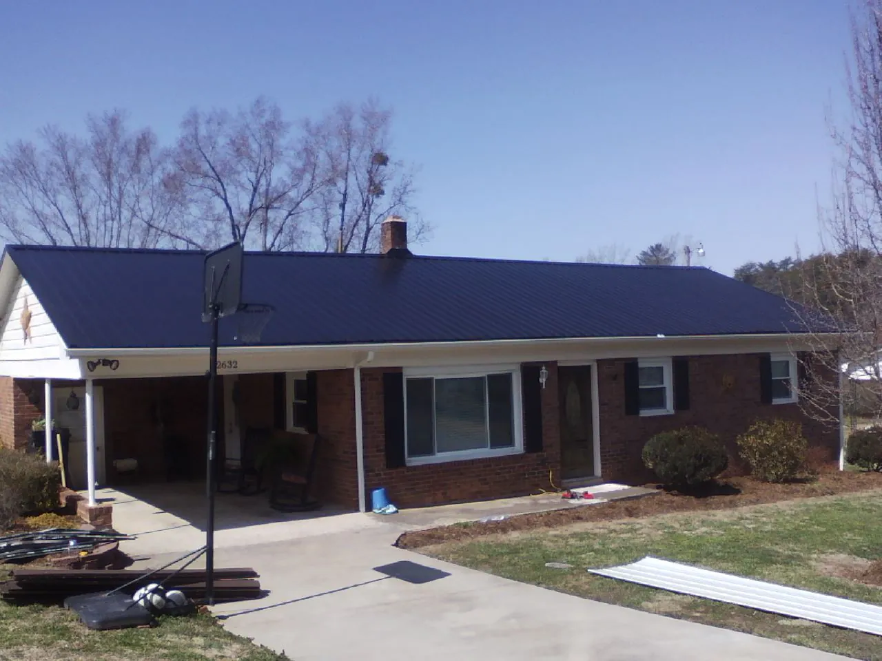 Finished dark blue metal roof on a brick ranch with a carport in Coffeyville