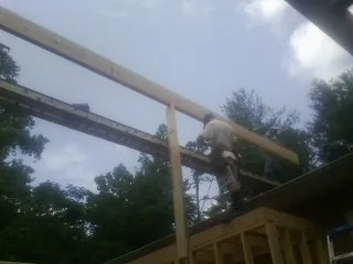 Carpenter setting a ridge beam over a new addition frame — Ice Dam Removal by Roofing Brothers in Coffeyville