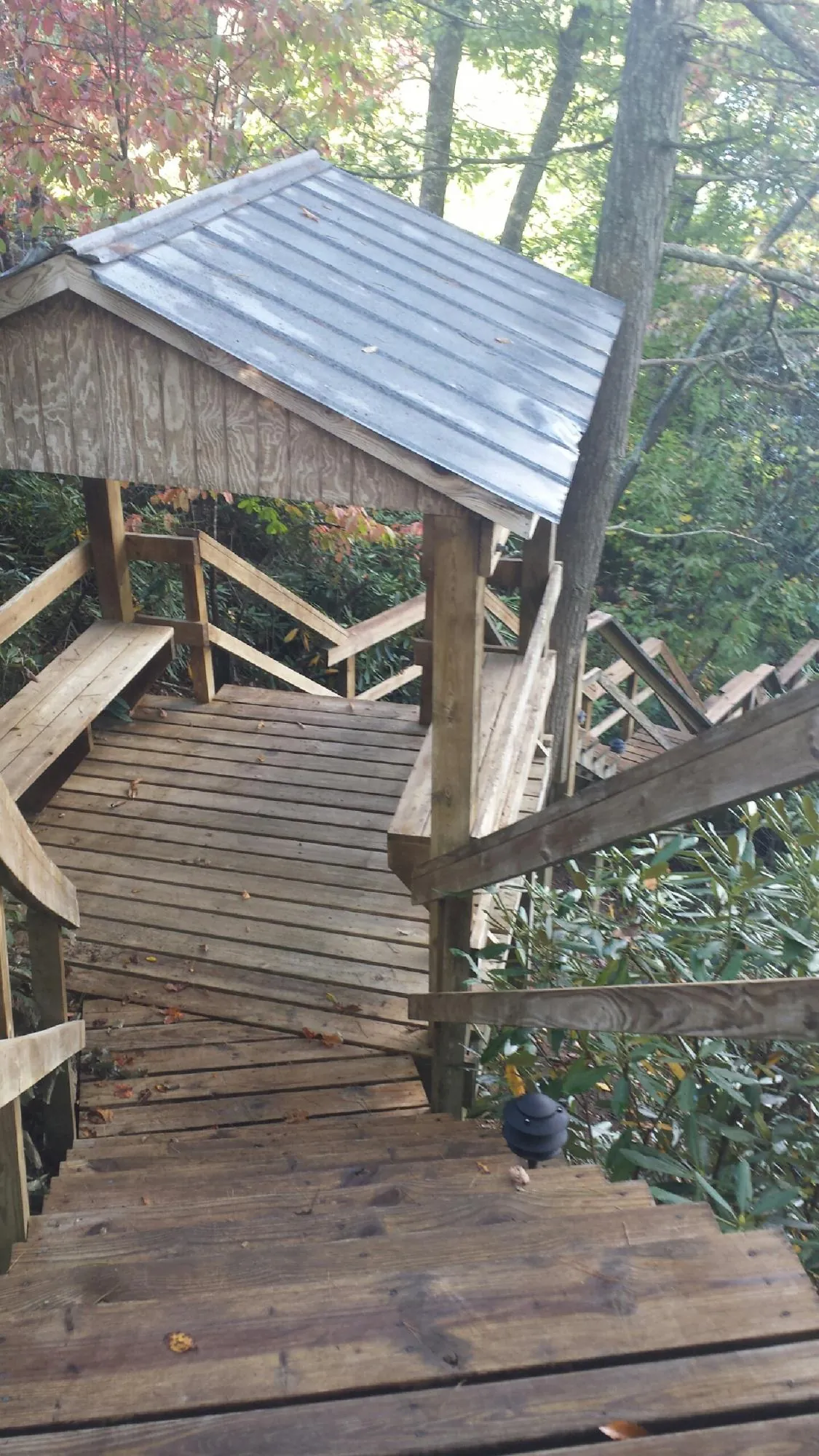 Metal roofed shelter over wooden steps on a wooded walkway — Skylight Repair & Installation work by our crew in Coffeyville
