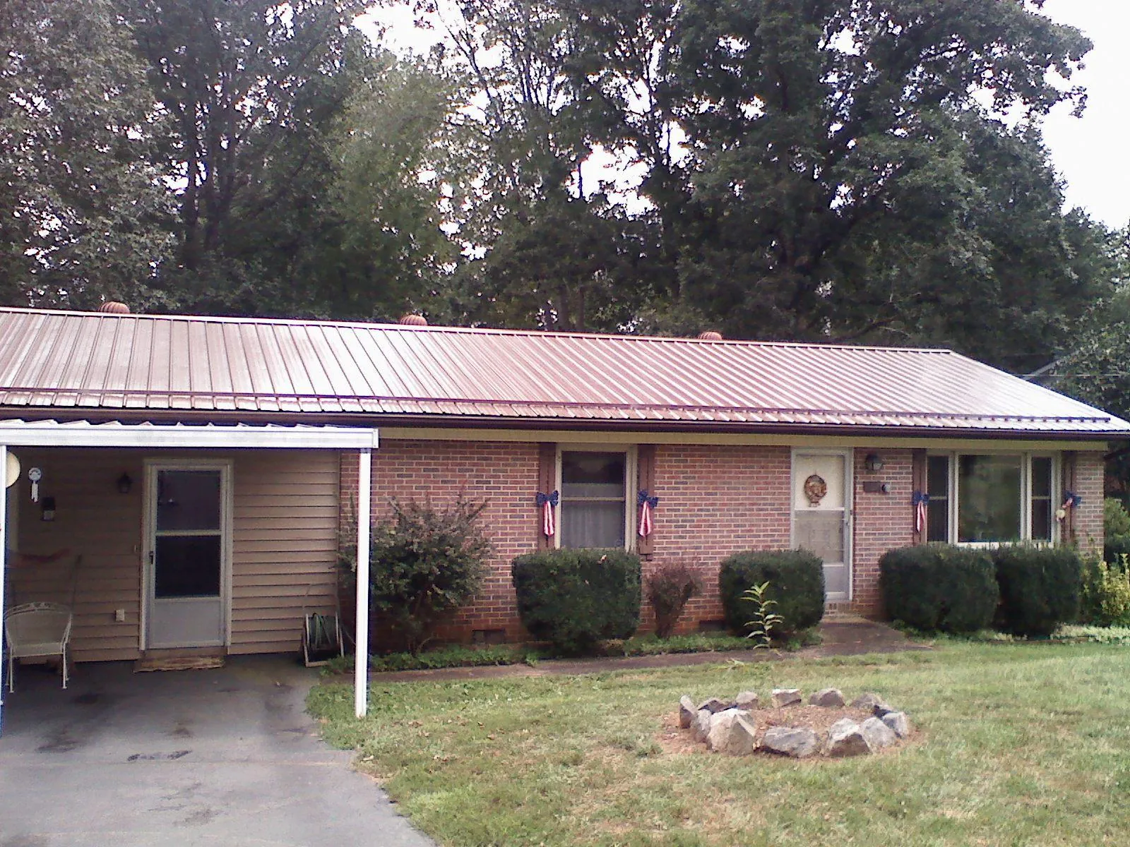Bronze metal roof and carport on a brick ranch home — Roof Repair work by our crew in Coffeyville